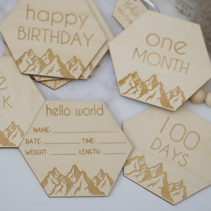 Hello world with baby stats, happy birthday, one month, 100 days, baby milestone signs in the shape of hexagons.
