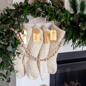 Stockings hanging on mantle with personalized stocking name tags, beaded garland and greenery
