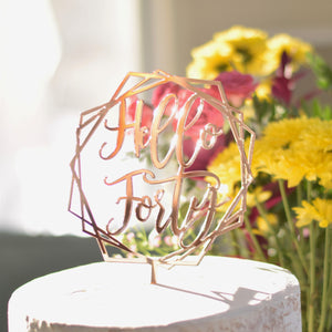 Mirrored rose gold cake topper on a cake with yellow flowers