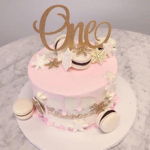 Sparkly gold One cake topper on a pink winter onederland cake