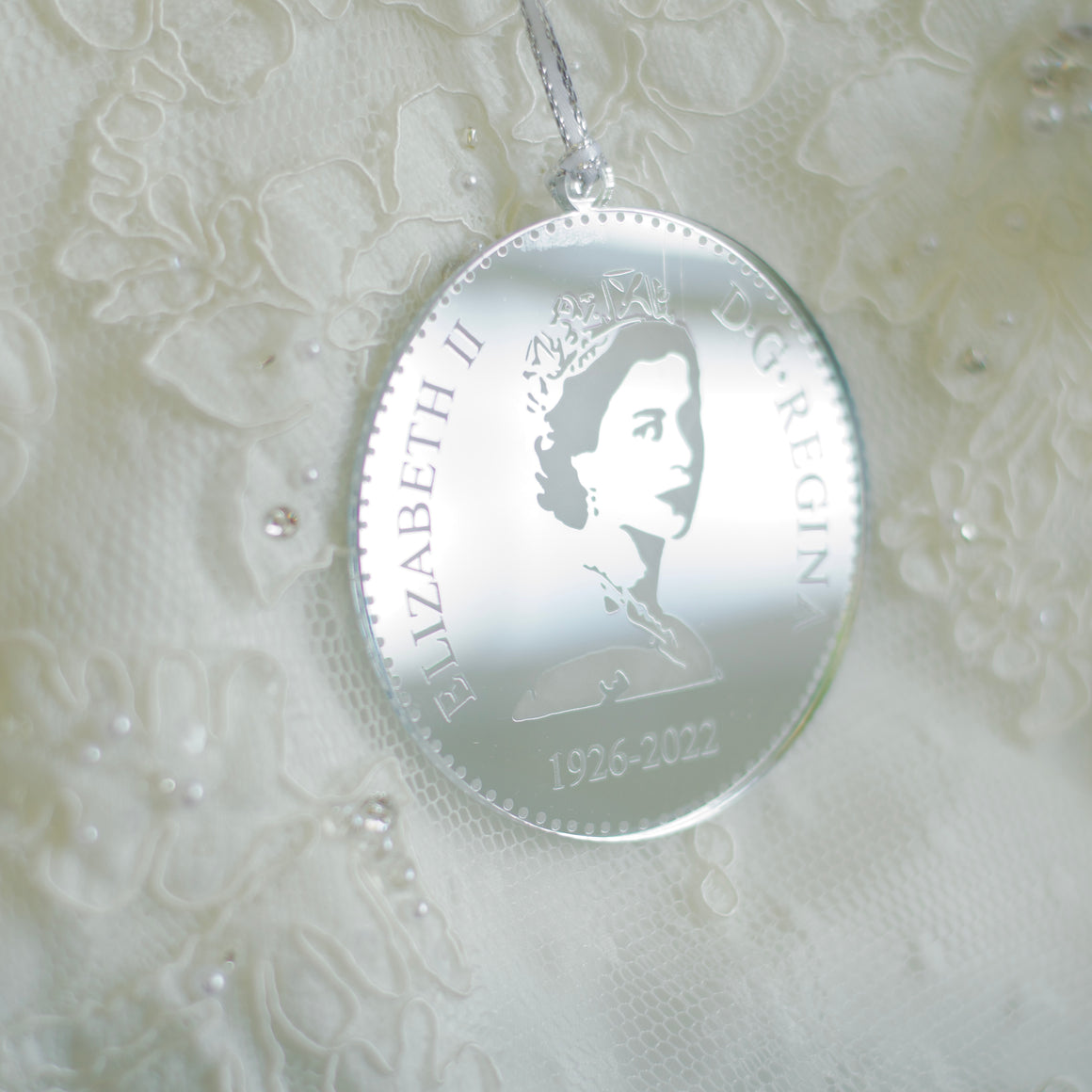 Silver Queen Elizabeth II Christmas tree ornament, appears as a replica of the back of a nickel or dime.