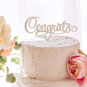 Congrats script cake topper on a white cake with florals