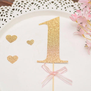 1 gold glitter cake topper on a white background with gold glitter heart accents