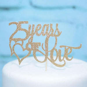 25 Year of Love with gold heart with gold sparkly font on a white cake with blue background