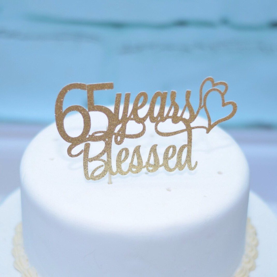 65 Years blessed with two hearts in gold glitter on white cake.