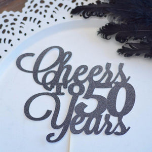 Cheers to 50 years black glitter cake topper on white plate background with black feathers