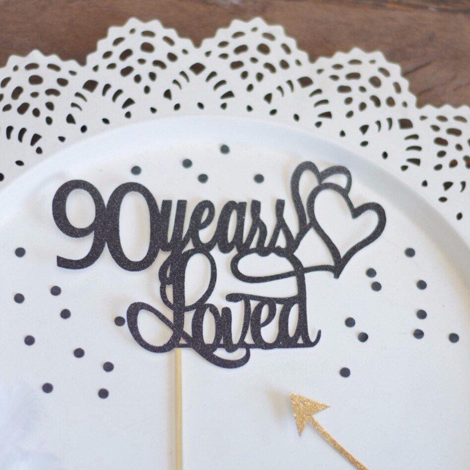 90 Years loved black sparkle cake topper with two intertwined hearts on white background