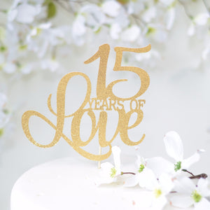 15 Years of Love gold glitter cake topper on a beautiful white cake with floral background