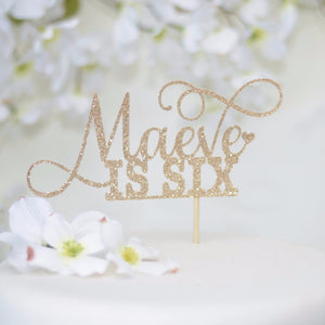 Maeve is six gold sparkle cake topper with delicate details