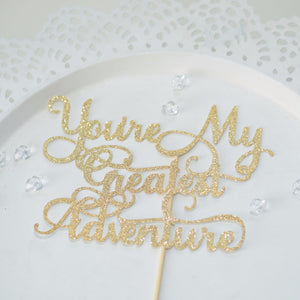 You're my Greatest Adventure gold glitter sparkle cake topper on white plate