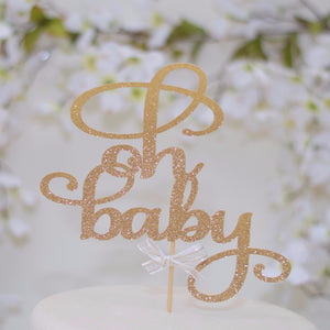 Oh Baby gold sparkle glitter cake topper on white cake with floral background