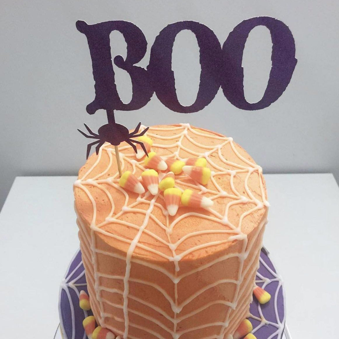 Boo black spider cake topper on orange and purple spiderweb cake