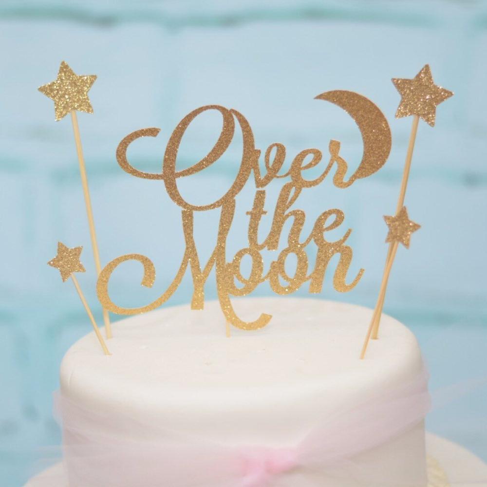 Over the moon cake topper with star and moon details in sparkly gold glitter