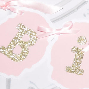 B and i gold sparkle banner letters on pink background