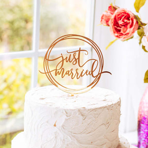 Just married cake topper on a white wedding cake and flowers