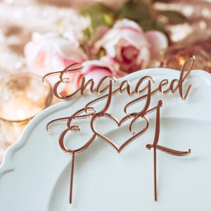 rose gold engagement party decorations with a cake topper, candle and pink flowers