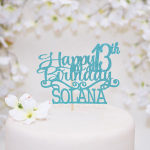 Turquoise happy birthday cake topper on a white cake with white flowers
