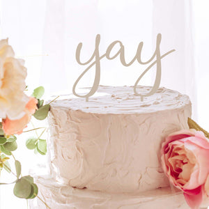yay cake topper on a white cake with flowers