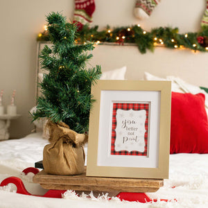 Gold framed christmas sign on bed with christmas tree